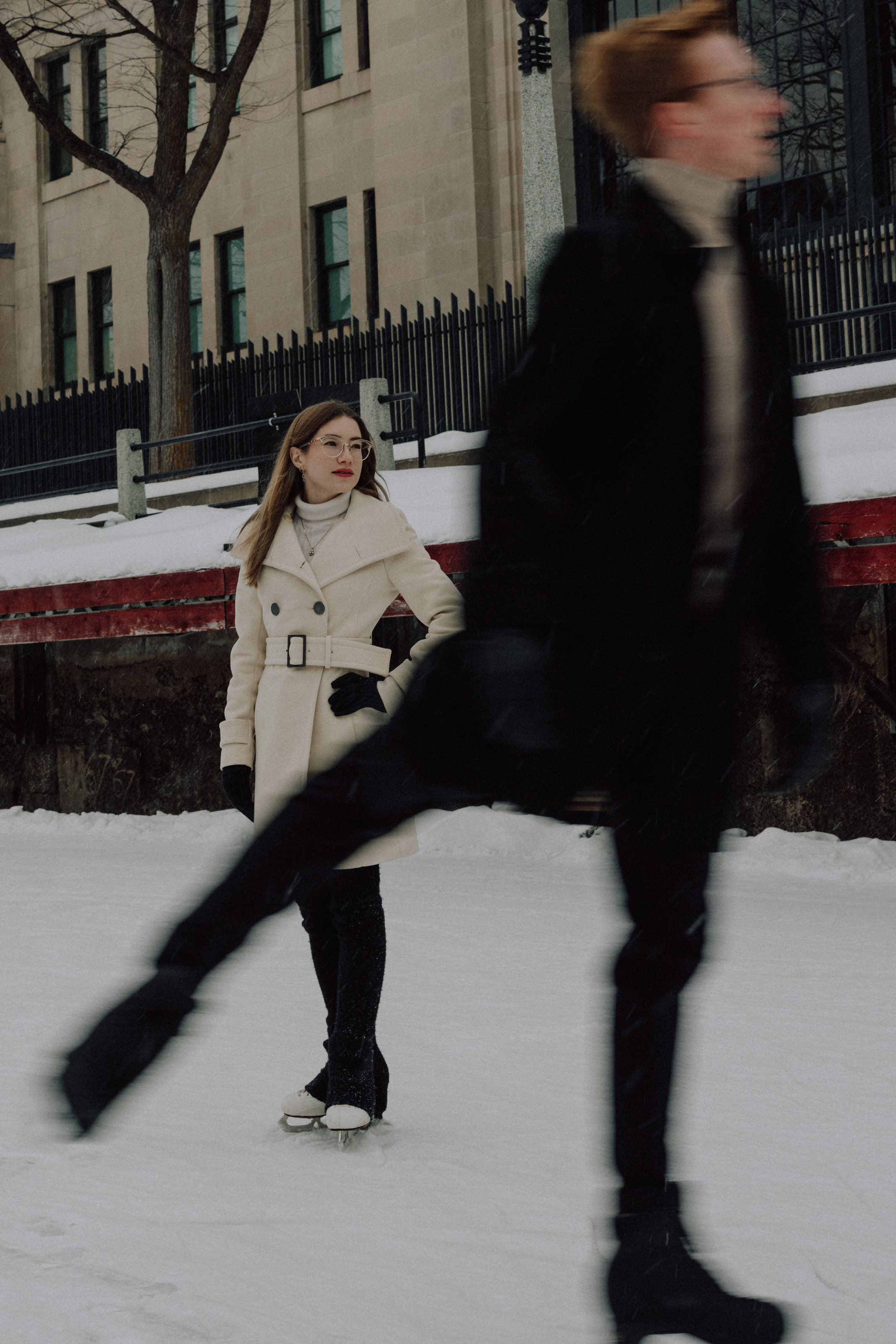 Kaitlyn standing on the Rideau Canal skateway as Alex skates past in a blur